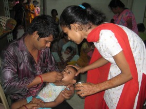 Nasreen helping a father give deworming medicine